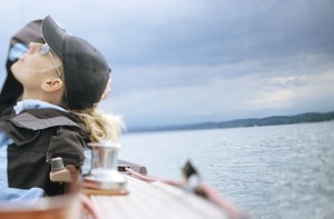 Woman on boat looking up at cloudy sky