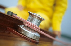 Close-up of rope around capstan with person in yellow waterproofs